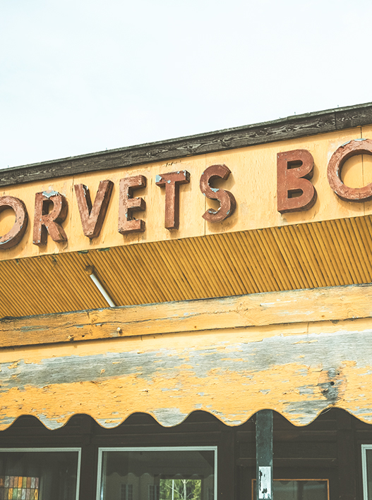 Facade med store bogstaver “DRVET’S” og “BO” over orange stribet vinduesparti under blå himmel.